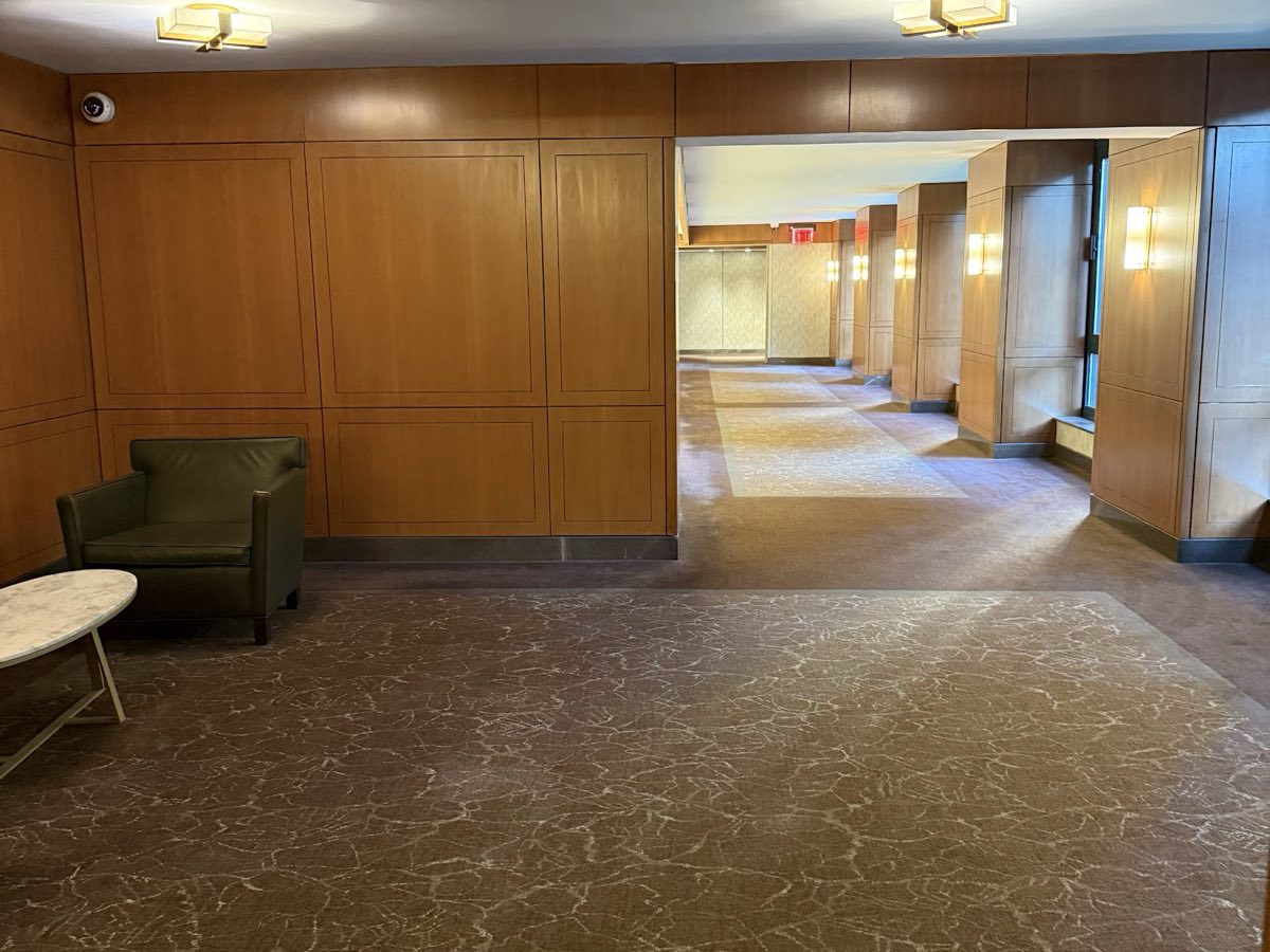 A carpeted hallway on the 7th floor with a green armchair and wood panelling