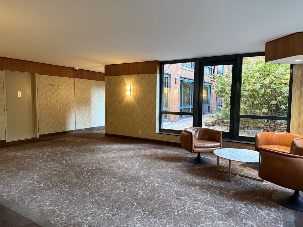 A seating area with leather chairs and a Village Tower sign on the far wall
