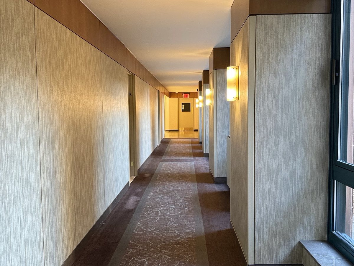 A long hallway with windows on the right, leading to the Village Tower elevator